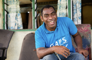 A smiling Fijian man with mobility aids